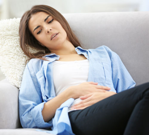 young woman suffering from abdominal pain at home